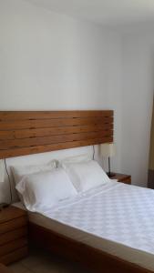 un grande letto con testiera in legno e lenzuola bianche di Meis Hotel a Bitez