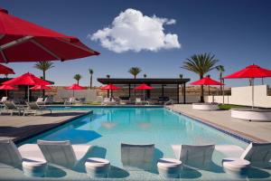 a swimming pool with chairs and red umbrellas at Four Points by Sheraton Yuma in Yuma