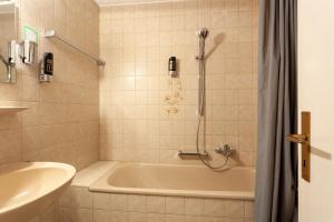 uma casa de banho com uma banheira, um chuveiro e um lavatório. em Hotel-Landgasthof SchachenerHof Lindau Konditorei Biergarten em Lindau