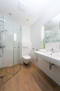 łazienka z toaletą, 2 umywalkami i prysznicem w obiekcie Naturhotel Edelweiss Wagrain w mieście Wagrain