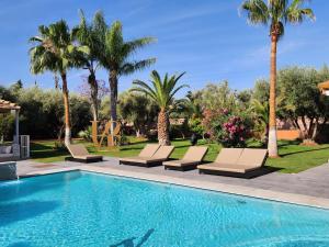 a swimming pool with lounge chairs and palm trees at Domaine K Marrakech in Marrakesh