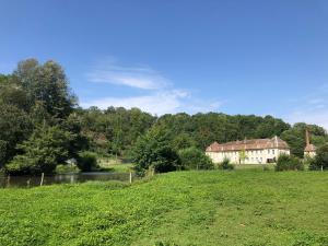 ein Grasfeld mit einem Haus und einem Fluss in der Unterkunft Abbaye de l'Etanche - 2 chambres d'hôtes - Un cadre naturel exceptionnel - 