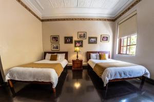 two beds in a room with two windows at Hotel Cuenca in Cuenca