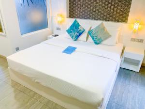 a bedroom with two beds with white sheets and blue pillows at Velana Beach Hotel Maldives in Maafushi