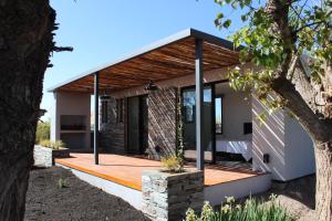 a house with a wooden deck and a tree at Lodwine Lodge Apartments in Ciudad Lujan de Cuyo