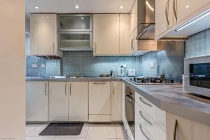 uma cozinha com armários brancos e electrodomésticos de aço inoxidável em Rawlinson Road 10A em Oxford