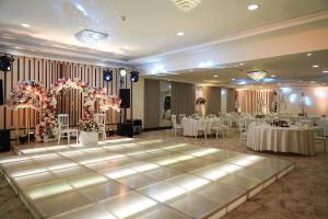 Salón de baile con mesas y sillas y pista de baile en MENA Tyche Hotel Amman en Amán