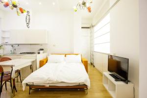 a white bedroom with a bed and a kitchen at Bilocale Bocconi - silenzioso - piano alto in Milan