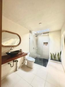een badkamer met een wastafel, een toilet en een spiegel bij The Dulu Penida Cottage in Nusa Penida