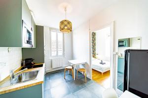 a kitchen with a sink and a table in a room at Le petit Raspail-Appartement rénové-Gratte-Ciel in Villeurbanne