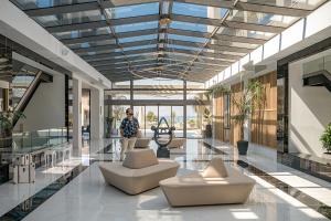 une femme debout dans un hall avec des chaises et des tables dans l'établissement Myrion Beach Resort & Spa - Adults Only, à Gerani