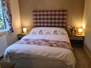 a bed in a room with two tables and two lamps at Tulip Lodge with Hot Tub in Malton