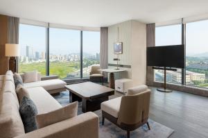 a living room with a couch and a flat screen tv at Shaoxing Marriott Hotel Shangyu in Shaoxing