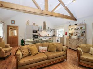 a living room with a couch and a kitchen at Brookside Byre in Brancepeth