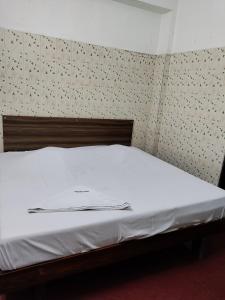 ein weißes Bett mit einem Kopfteil aus Holz im Schlafzimmer in der Unterkunft Jeyanthi Tower Vellore in Vellore