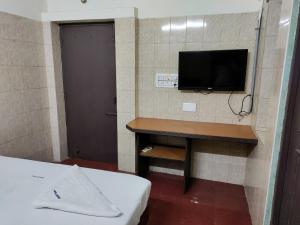 Zimmer mit einem TV und einem Schreibtisch mit einem Bett. in der Unterkunft Jeyanthi Tower Vellore in Vellore