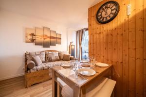 a living room with a table and a clock on the wall at Appartement Morillon 4pers in Morillon