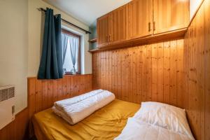 een slaapkamer met een bed met een houten muur bij Appartement Morillon 4pers in Morillon