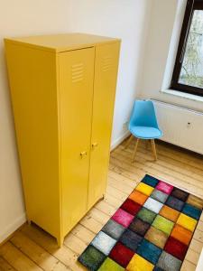un armario amarillo y una silla azul en una habitación en SECRET HIDEAWAYS Design Apartment ARTstudio 5 nahe City l Messe l Hbf, en Duisburg