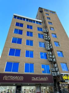 wysoki budynek z niebieskimi oknami w obiekcie برج موجان السكني التجاري w mieście Chamis Muszajt