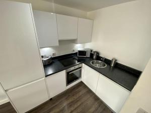 a small kitchen with white cabinets and a sink at Liverpool Waterfront Apartment in Liverpool