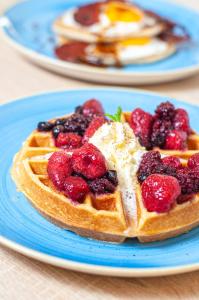 a waffle with berries on a blue plate on a table at Los Corales Beach Village Punta Cana - The original in Punta Cana
