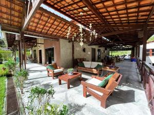 un patio esterno con sedie, tavoli e tetto in legno di Pousada Monte Flor Guaramiranga CE a Guaramiranga
