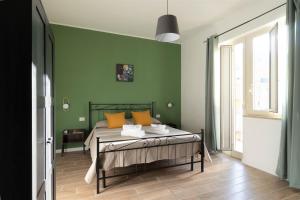 een slaapkamer met groene muren en een bed met oranje kussens bij Merylì House in Napels