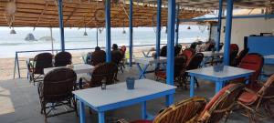 a restaurant on the beach with tables and chairs at The Tito's Blue Sky Beach resort in Agonda