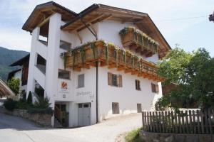 - un grand bâtiment blanc avec un balcon en bois dans l'établissement Apartment Oberhauserhof, à Falzes