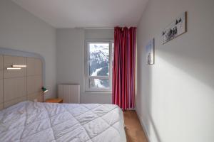 a bedroom with a bed and a window with red curtains at Flaine- Appartement 7 personnes in Flaine