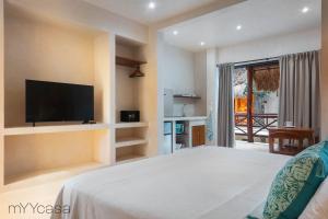 Un dormitorio con una cama grande y un televisor de pantalla plana. en Casa Yaakun, en Tulum
