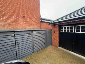 a garage with two garage doors and a brick building at Modern stylish studio flat near Leigh on sea. in Hadleigh