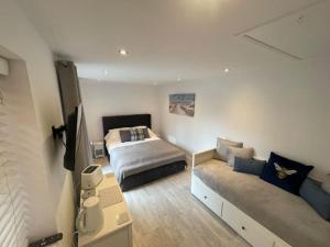 a bedroom with a bed and a couch at Modern stylish studio flat near Leigh on sea. in Hadleigh