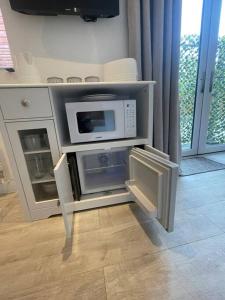 a kitchen with a microwave and an open refrigerator at Modern stylish studio flat near Leigh on sea. in Hadleigh