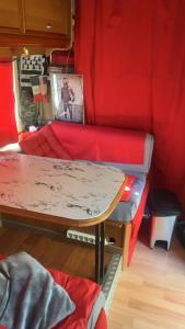 a living room with a red couch and a table at Camping car fixe dans la campagne in Pianottoli-Caldarello