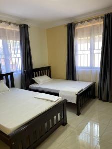 2 Betten in einem Zimmer mit 2 Fenstern in der Unterkunft Munyonyo Apartment in Kampala