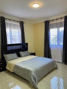 1 dormitorio con 1 cama grande y 2 ventanas en Munyonyo Apartment, en Kampala