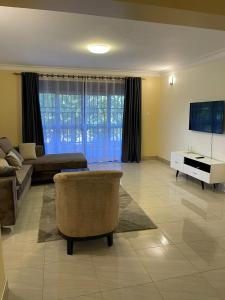 ein Wohnzimmer mit einem Sofa und einem TV in der Unterkunft Munyonyo Apartment in Kampala