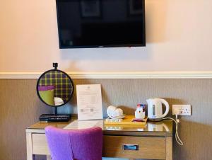 a desk with a mirror and a tv on a wall at Balmacara Hotel in Kyle of Lochalsh