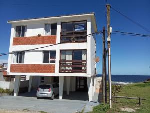 une maison blanche avec une voiture garée en face de l'océan dans l'établissement Apartamento 5 El Timon, à La Paloma