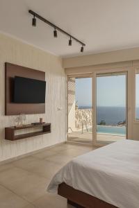 a bedroom with a flat screen tv on a wall at Apolis Villas & Suites Resort in Parga
