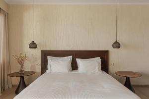 ein Schlafzimmer mit einem großen Bett mit zwei Tischen in der Unterkunft Apolis Villas & Suites Resort in Parga