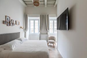 a white bedroom with a bed and a tv at Corso Caesar Suites in Rome