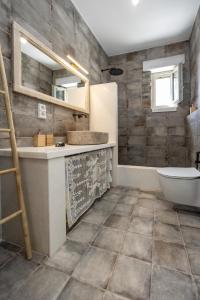 a bathroom with a toilet and a sink and a tub at Stone Haven Villas in Plaka