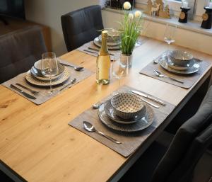 a table with plates and glasses and a bottle of wine at Ferienhaus Dorie in Dornumersiel