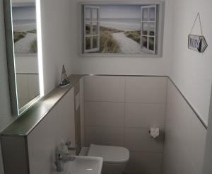 a bathroom with a toilet and two mirrors at Ferienhaus Dorie in Dornumersiel +14 photos