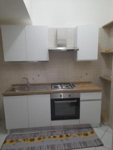 a kitchen with white cabinets and a stove and a sink at Casa Brezza marina in Barletta