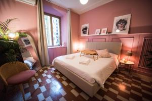 ローマにあるDomus Febo-Telesio Suiteのピンクの壁のベッドルーム(ベッド1台、椅子1脚付)