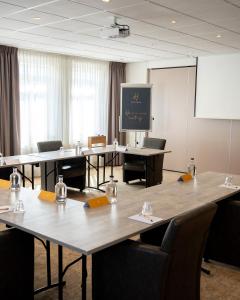 a conference room with tables and chairs and a screen at Hotel Alkmaar in Alkmaar